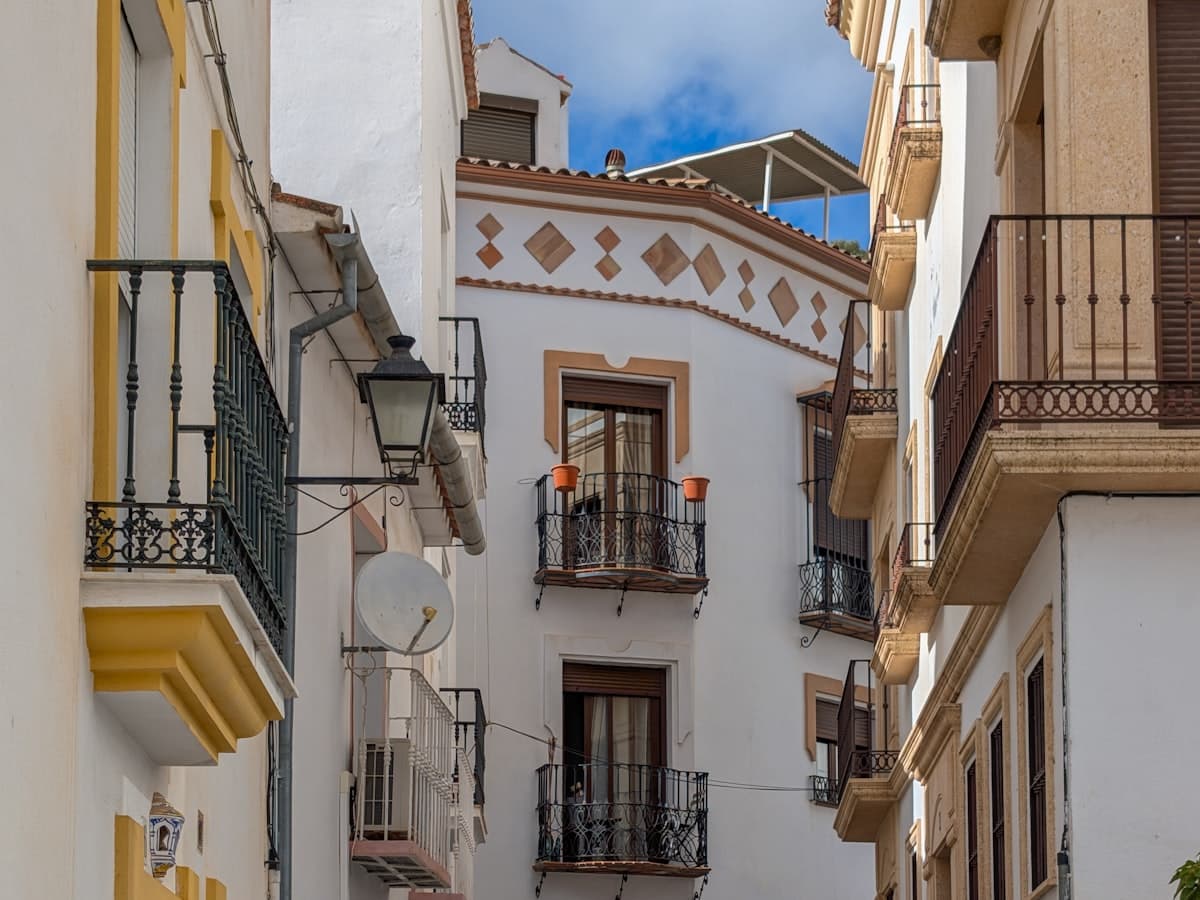 Calle estrecha entre edificios blancos con balcones