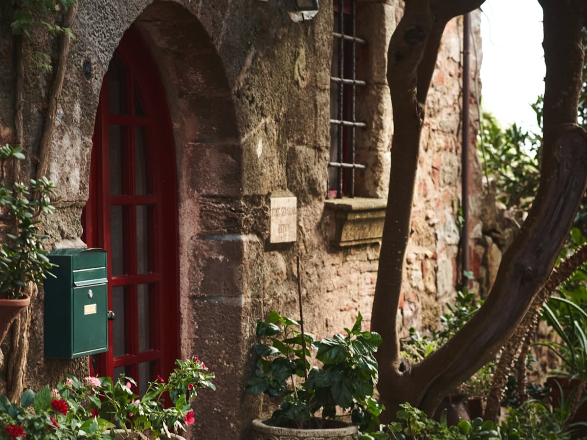 Casa de piedra con puerta roja rodeada de vegetación